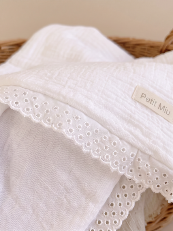 Manta blanca de muselina para bebé con delicada puntilla bordada y acabado artesanal de Petit Miu.