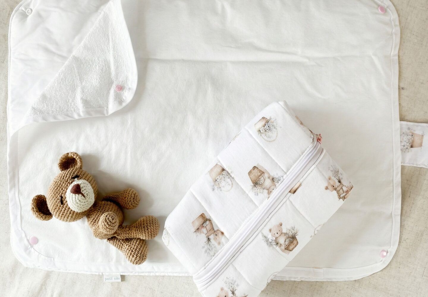 "Cambiador portátil blanco y neceser con estampa de ositos de Petit Miu para una organización maternal con estilo."
