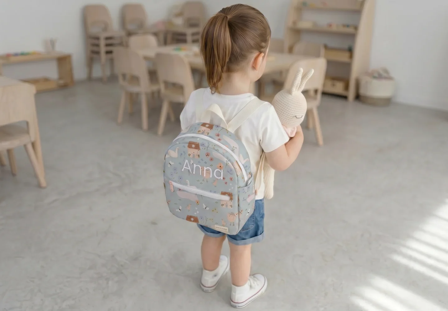 Niña con mochila para guardería personalizada impermeable con nombre bordado en escuela infantil