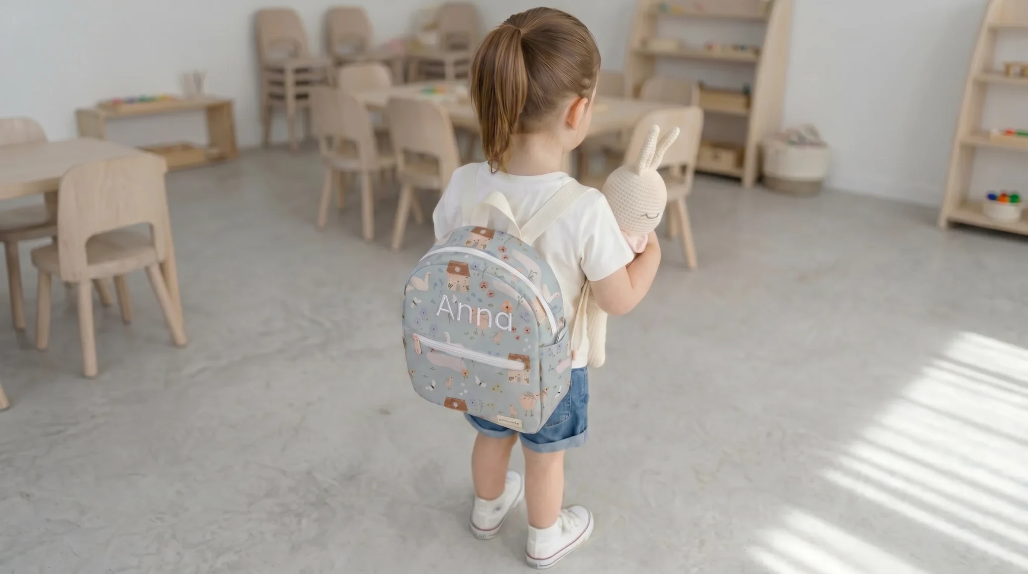 Niña con mochila para guardería personalizada impermeable con nombre bordado en escuela infantil
