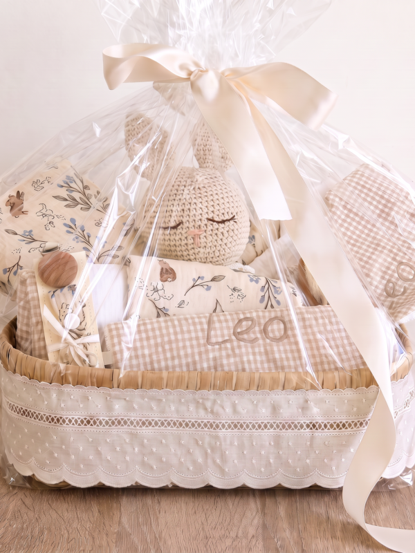 Canastilla personalizada para bebé con doudou, muselina, accesorios y nombre bordado, presentada como regalo de nacimiento